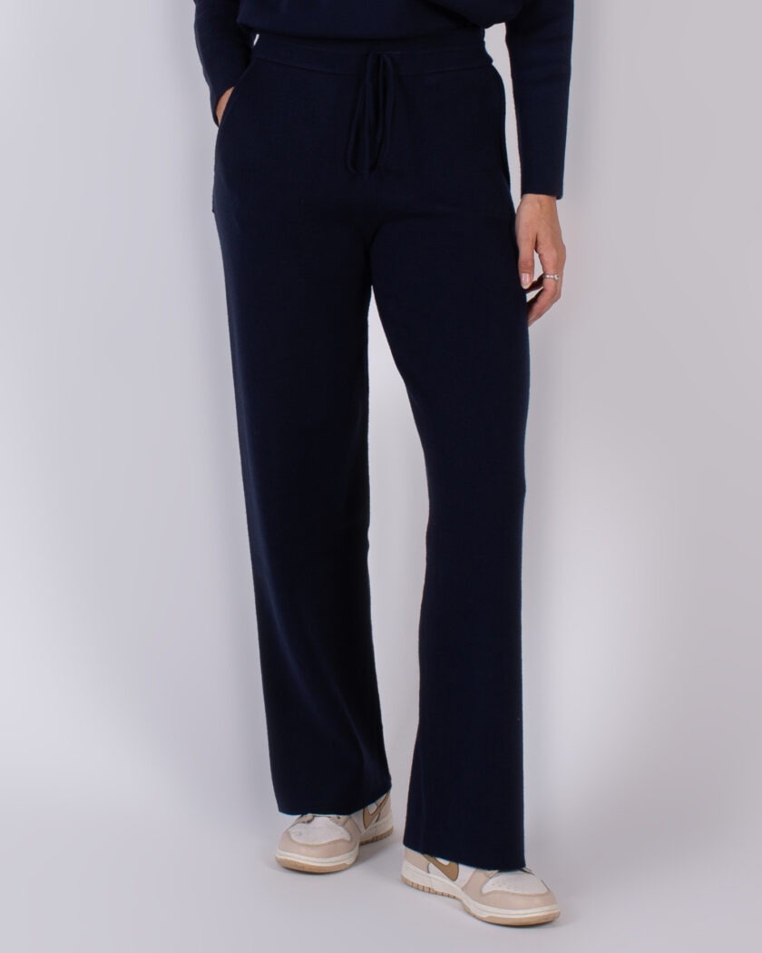 Vrouw draagt een donkerblauwe, rechte knit broek met trekkoord uit de Studio AW25-26 collectie.