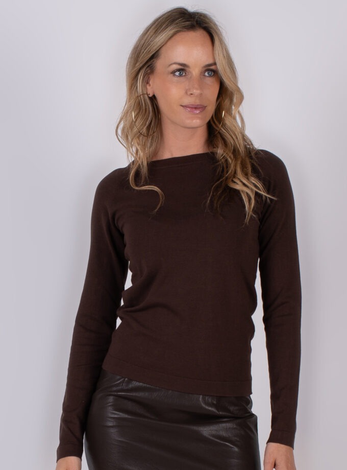 Vrouw draagt een donkerbruine, lange mouwen top en een donkerbruine leren rok uit de Studio AW25-26 collectie.