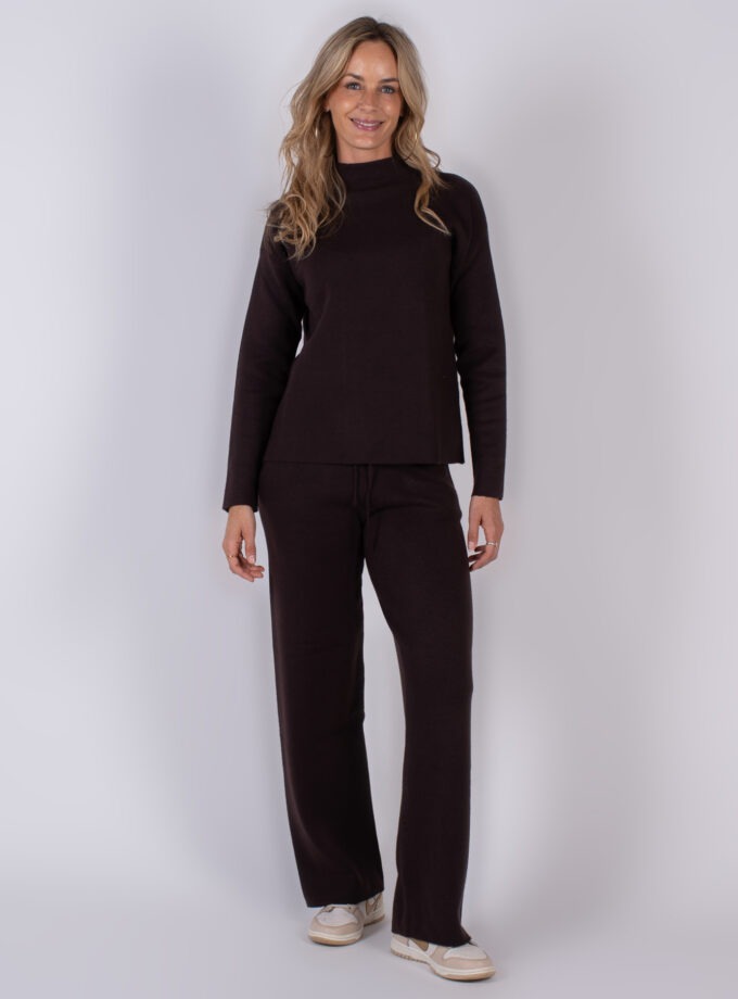 Vrouw draagt een donkerbruine loungetop met bijpassende broek uit de Studio AW25-26 collectie.