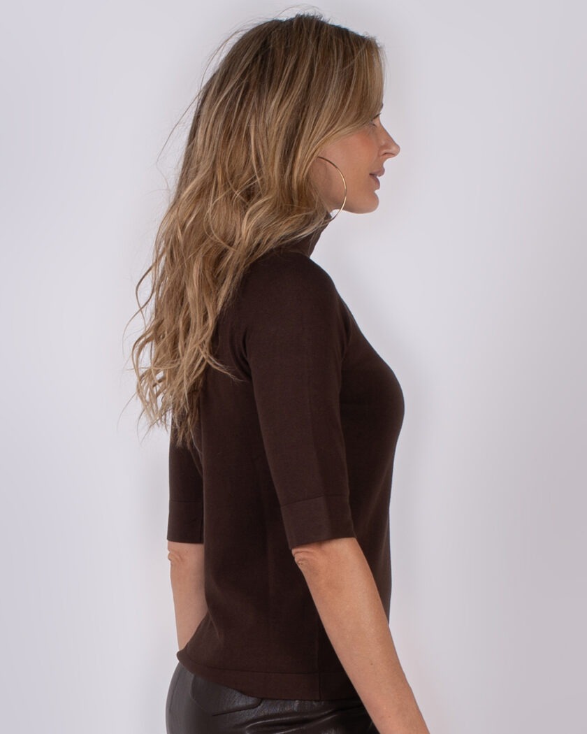 Vrouw in profiel met lang golvend haar draagt een donkerbruine top met halve mouwen uit de Studio AW25-26 collectie.