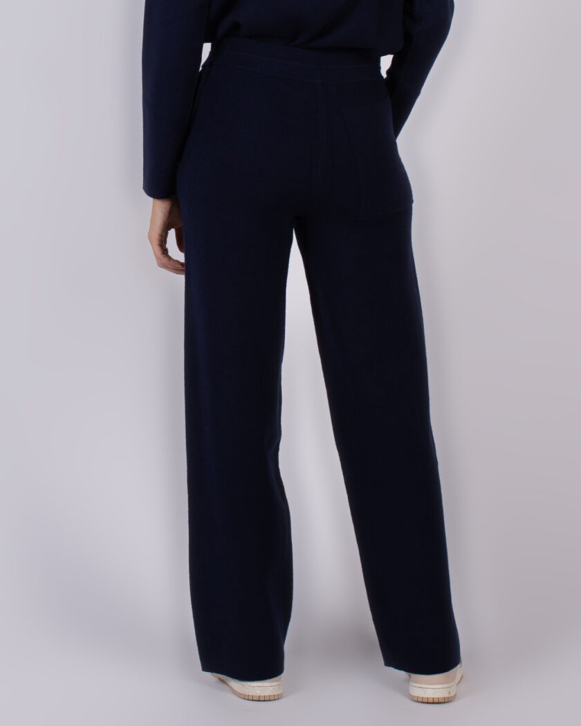 Achteraanzicht van een model in een donkerblauwe, wijde pantalon uit de Studio AW25-26 collectie.