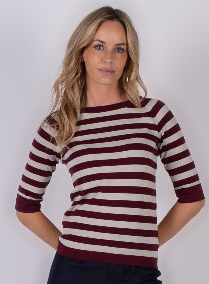 Vrouw draagt een bordeauxrood met beige gestreepte top met driekwartmouwen uit de Studio AW25-26 collectie.