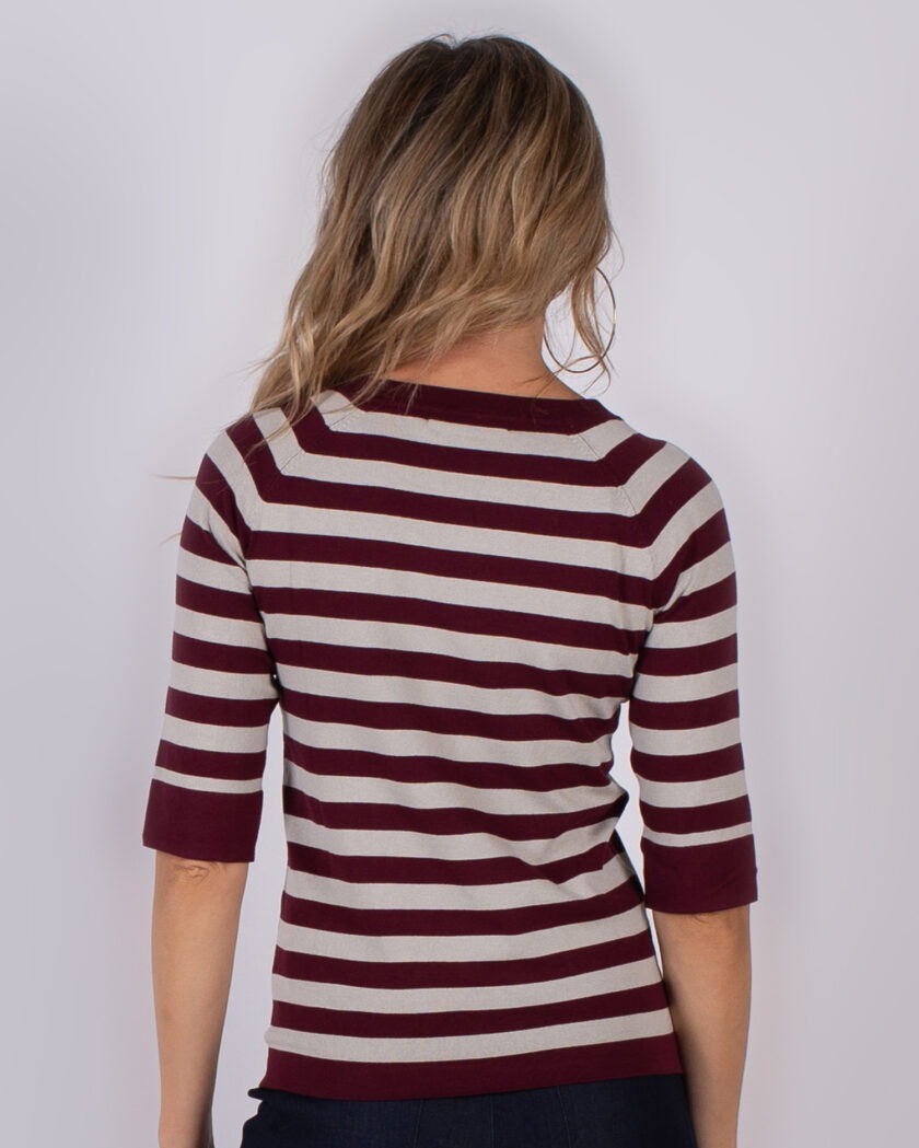 Vrouw van achteren gezien met halflang haar, gekleed in een bordeauxrood met beige gestreepte top met driekwartsmouwen.