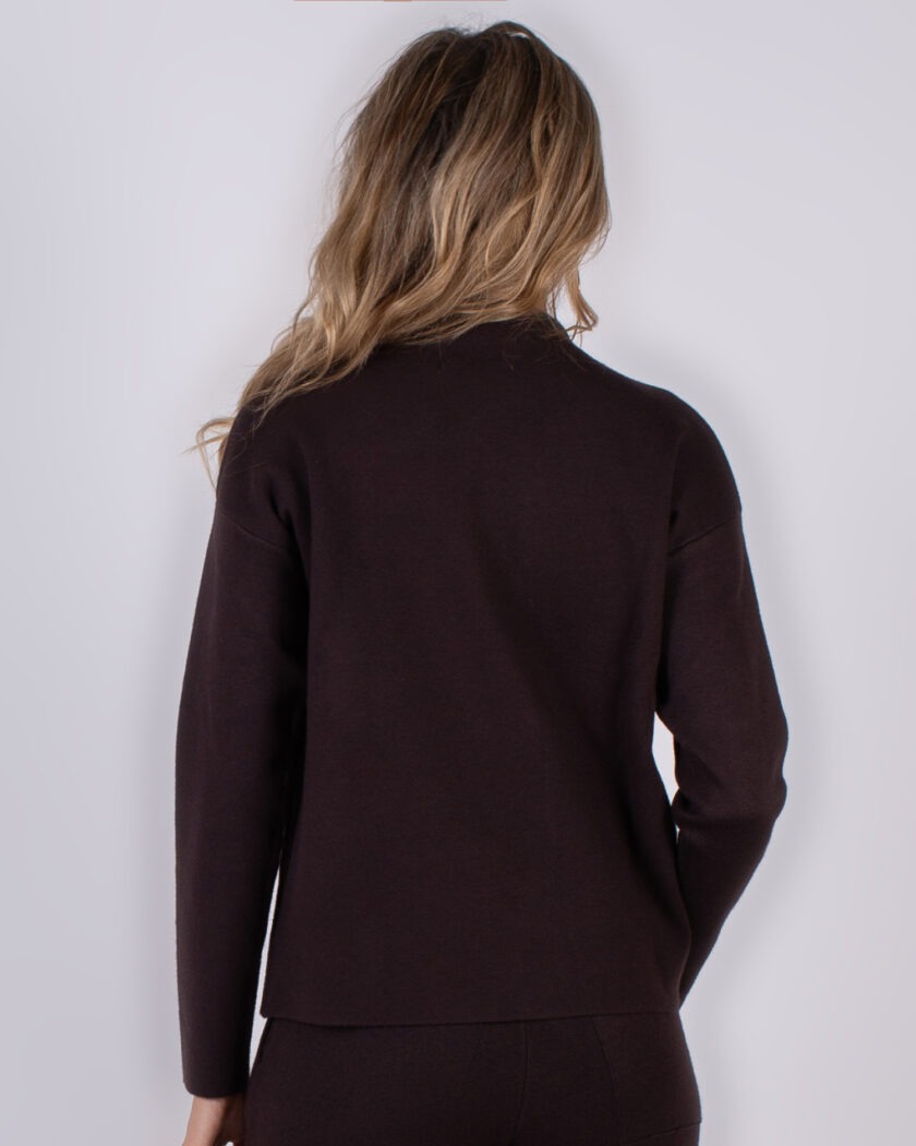 Model gezien van achteren in een donkerbruine, lange mouwen top uit de Studio AW25-26 collectie.