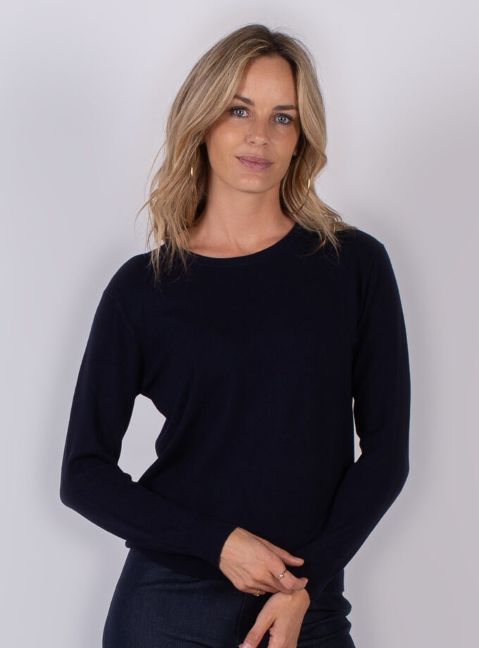 Vrouw draagt een donkerblauwe, lange mouwen trui uit de Studio AW25-26 collectie.