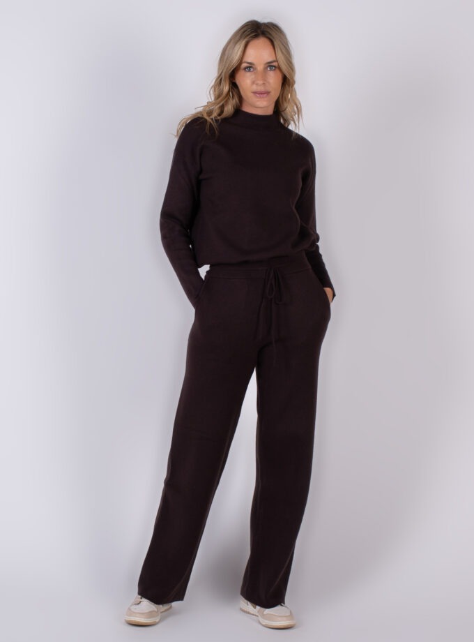 Vrouw poseert in een donkerbruine, comfortabele knitwear-set met lange mouwen en wijde broek uit de Studio AW25-26 collectie.