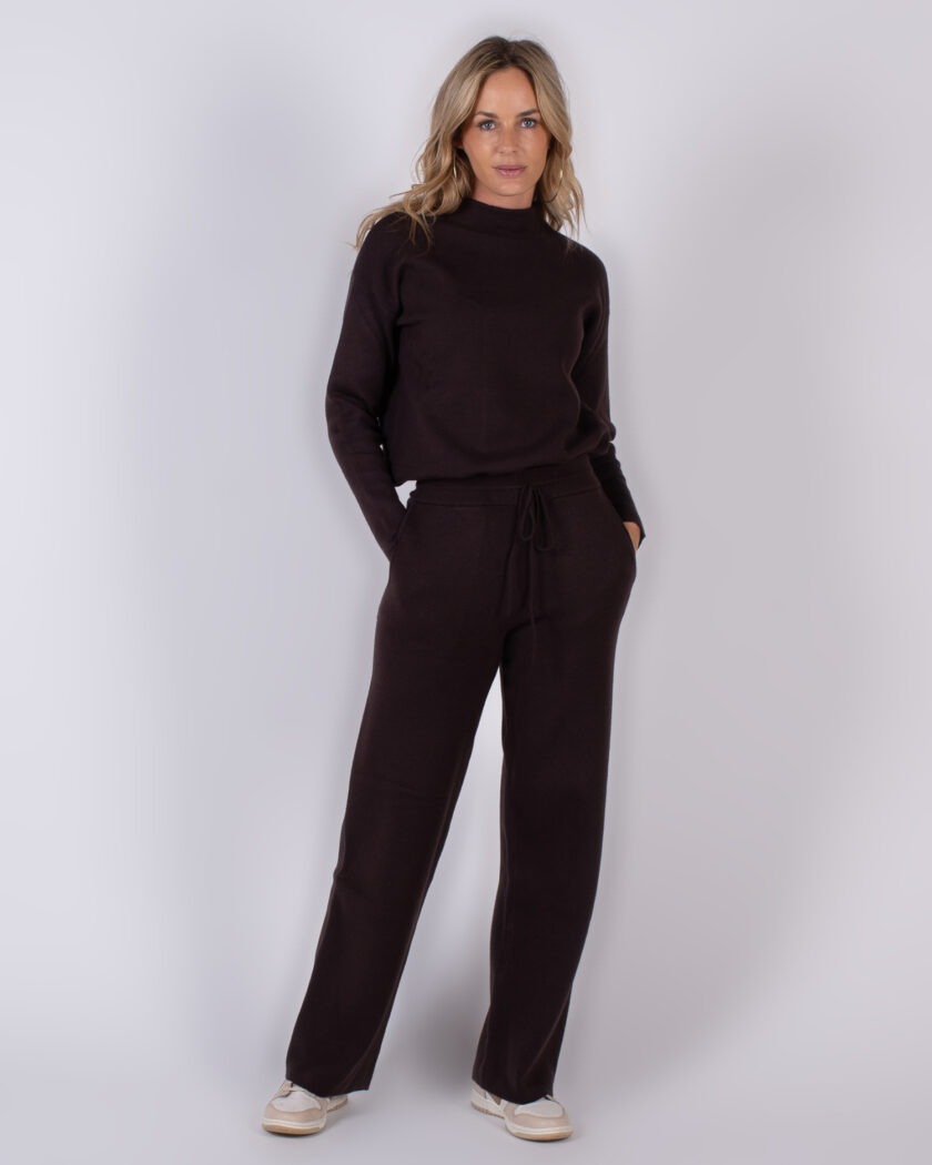 Vrouw poseert in een donkerbruine, comfortabele knitwear-set met lange mouwen en wijde broek uit de Studio AW25-26 collectie.