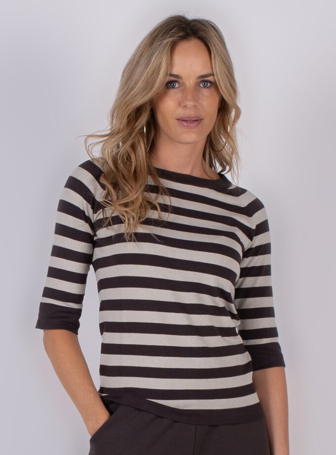 Vrouw met lang blond haar draagt een zwart-wit gestreepte top met driekwart mouwen uit de Studio AW25-26 collectie.