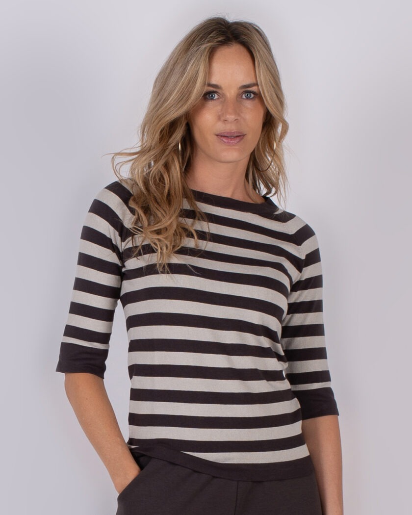 Vrouw met lang blond haar draagt een zwart-wit gestreepte top met driekwart mouwen uit de Studio AW25-26 collectie.