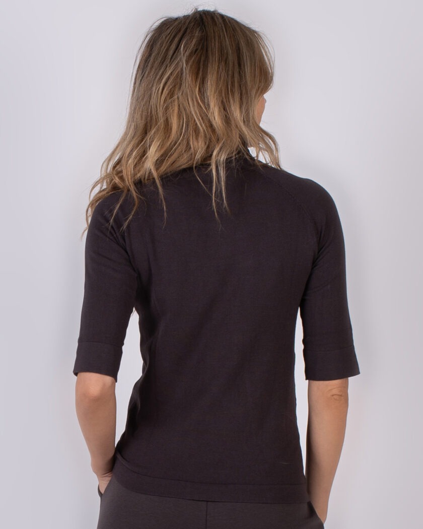 Vrouw van achteren in een donkerkleurige, halfmouw trui uit de Studio AW25-26 collectie.