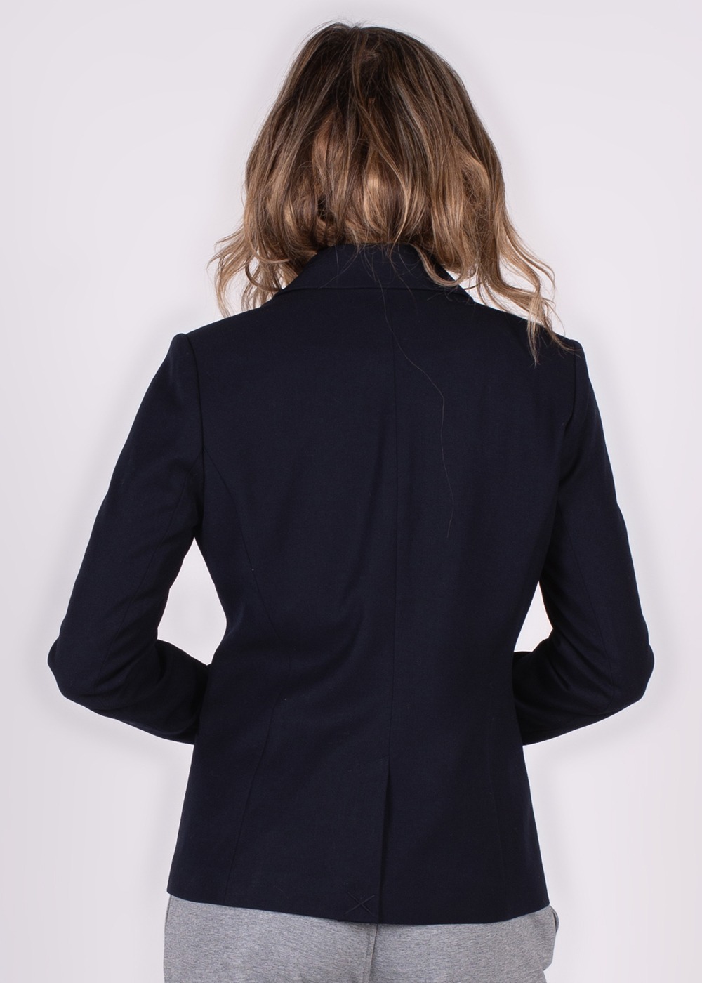 Achteraanzicht van een persoon met halflang haar die een donkere Nikko-blazer draagt.