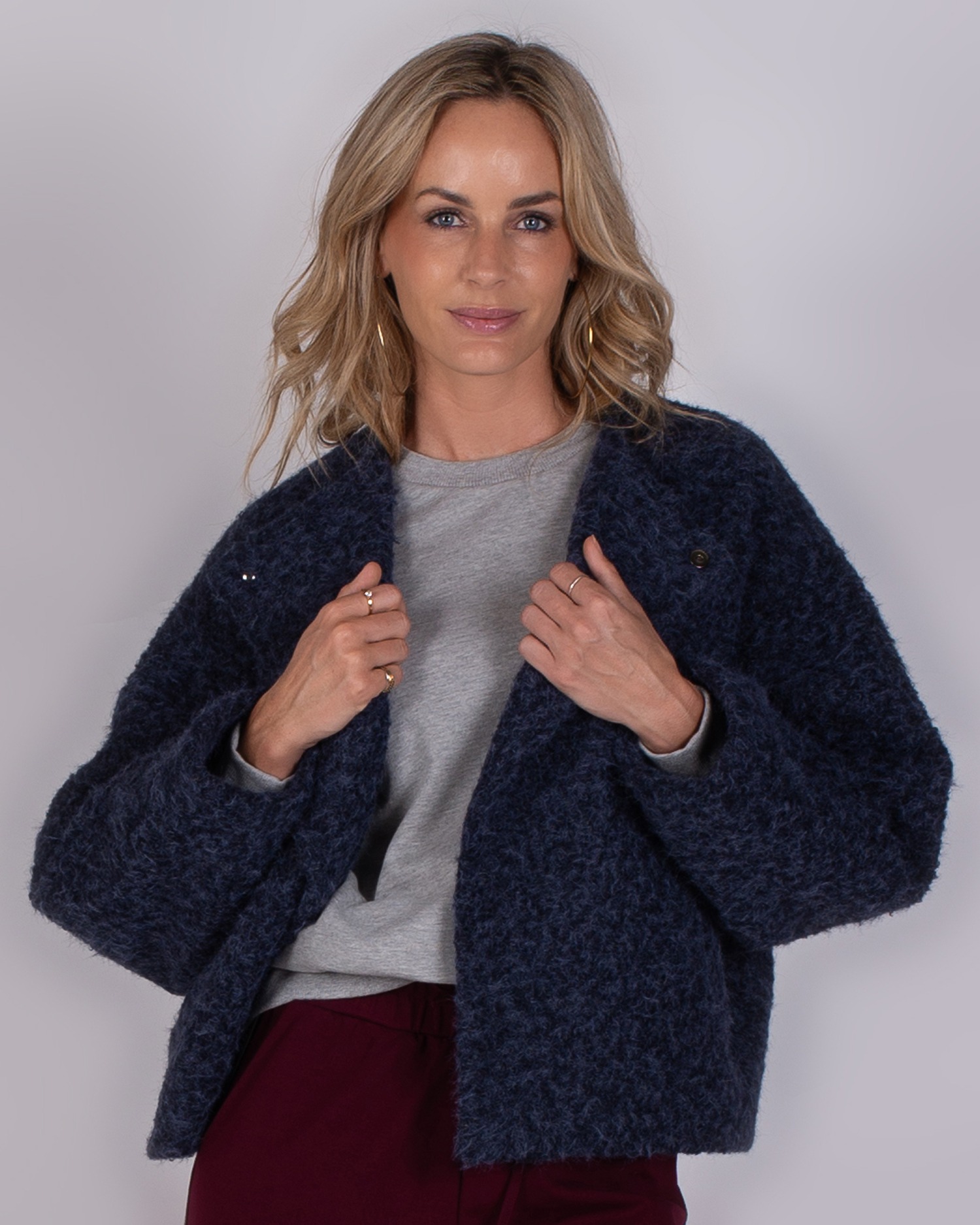 Studio_AW25-26-1 Vrouw draagt een donkerblauwe, wollige jas uit de Studio AW25-26 collectie.