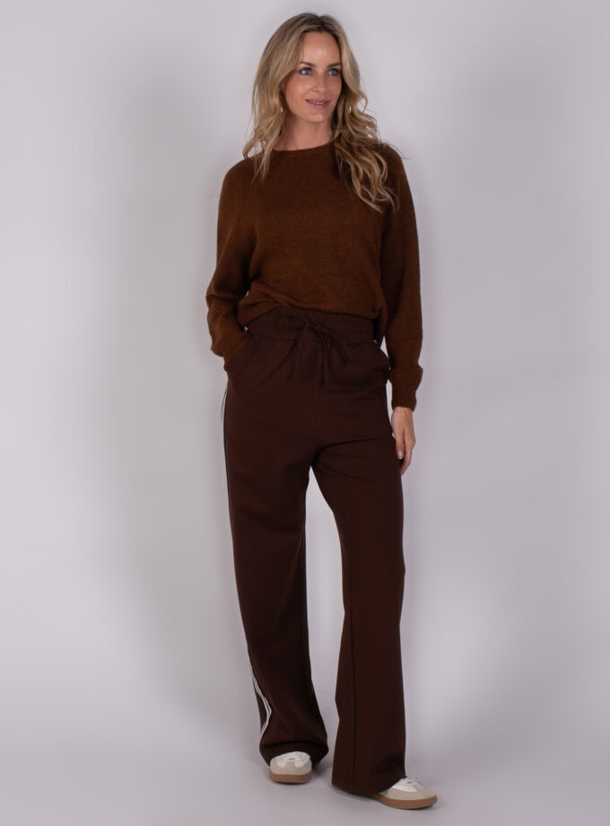 Vrouw draagt een donkerbruine trui en bijpassende wijde broek met sportieve strepen, look Studio_AW25-26-118.