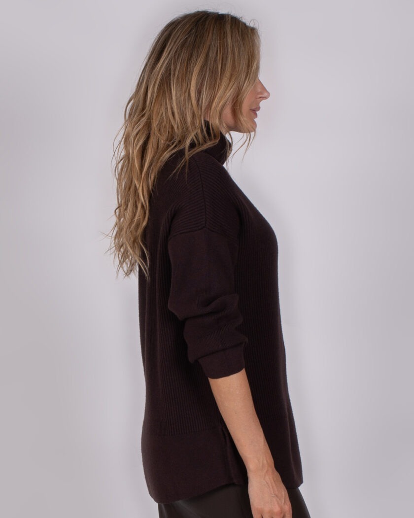 Vrouw met lang golvend haar draagt een donkerpaarse coltrui van Studio AW25-26-283, in zijaanzicht tegen een neutrale achtergrond.