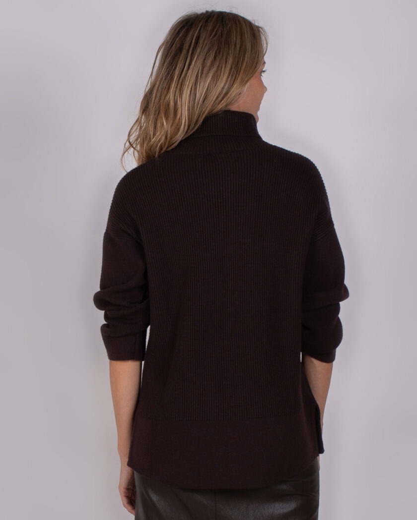 Vrouw van achteren in een donkerbruine coltrui met opgerolde mouwen uit de Studio AW25-26 collectie.