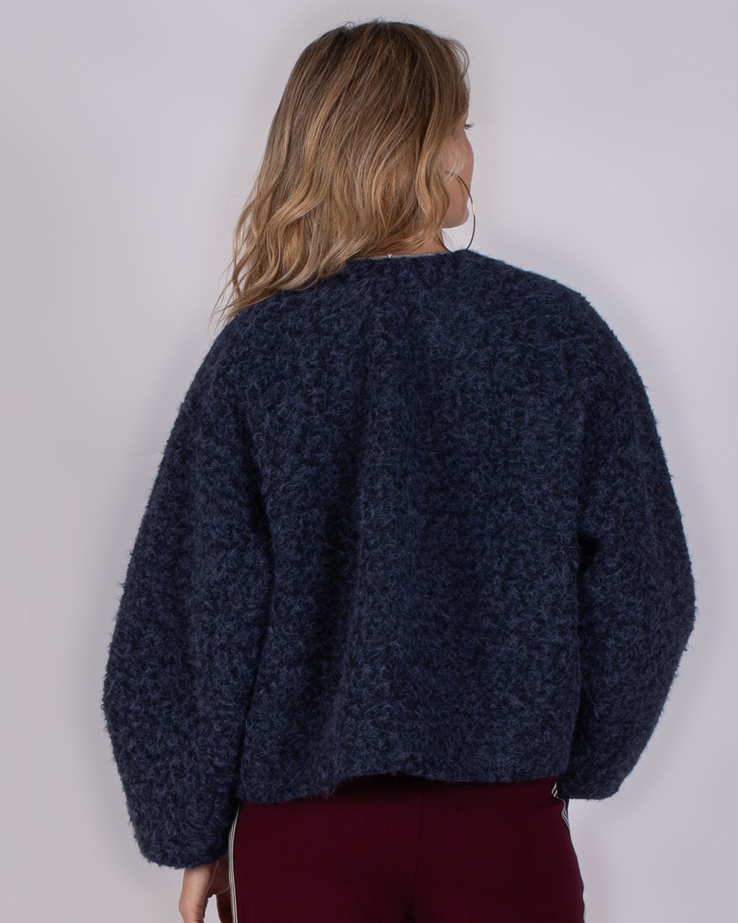 Studio_AW25-26-5 Achteraanzicht van een vrouw die een donkerblauwe, wollen trui uit de Studio AW25-26 collectie draagt.