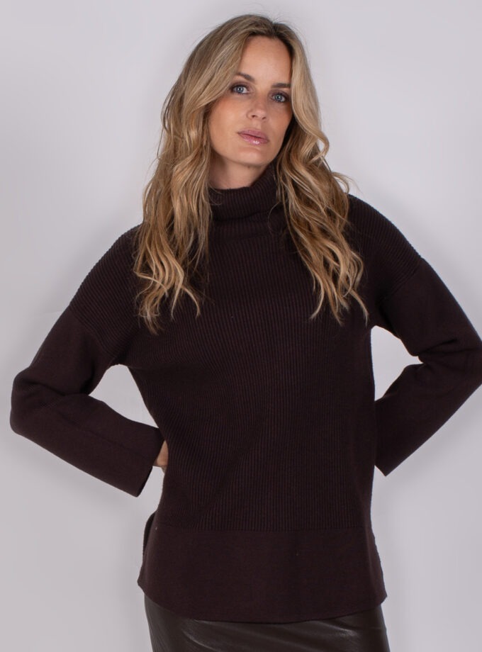 Vrouw draagt een donkerpaarse coltrui uit de Studio AW25-26 collectie tegen een neutrale achtergrond.