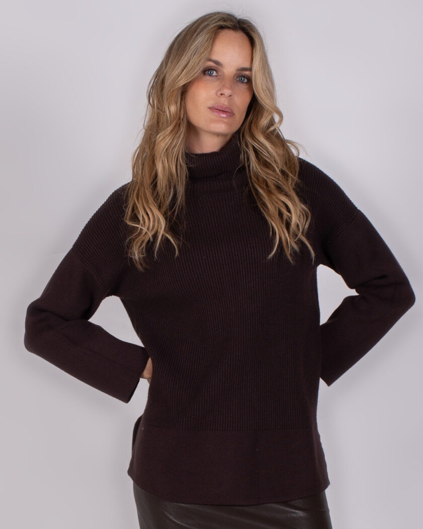Vrouw draagt een donkerpaarse coltrui uit de Studio AW25-26 collectie tegen een neutrale achtergrond.