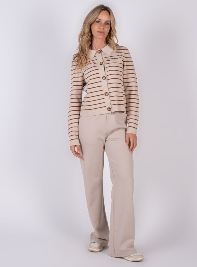 Vrouw draagt een beige outfit met een gestreept vest en wijde broek uit de Studio AW25-26 collectie.