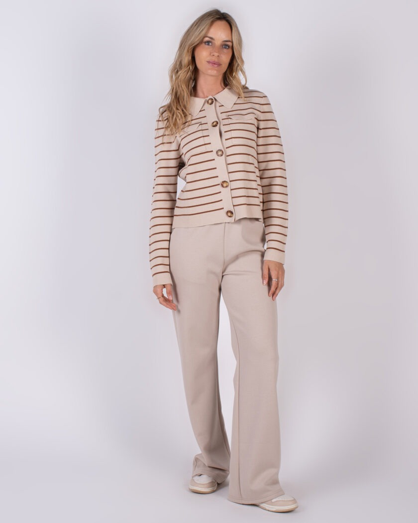 Vrouw draagt een beige outfit met een gestreept vest en wijde broek uit de Studio AW25-26 collectie.