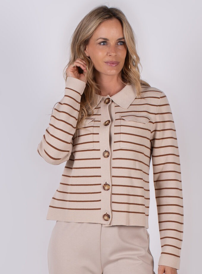 Vrouw draagt een beige vest met bruine horizontale strepen en grote knopen uit de Studio AW25-26 collectie.