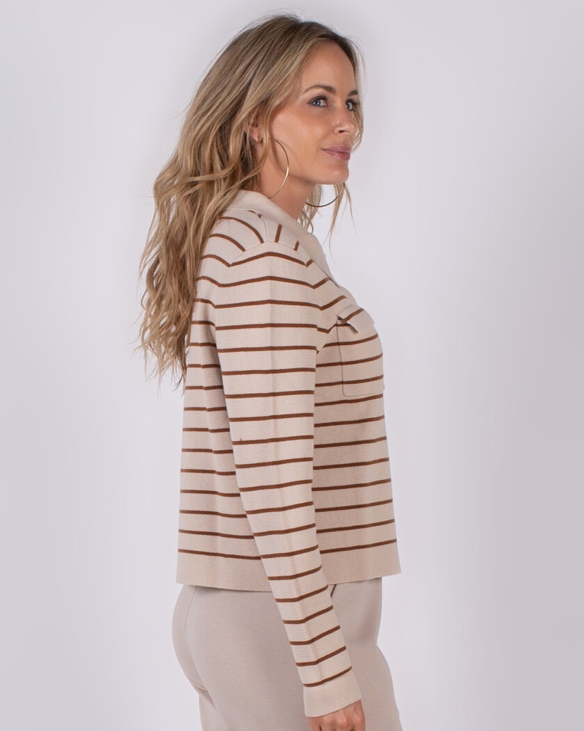 Vrouw in zijaanzicht draagt een beige trui met bruine strepen uit de Studio AW25-26 collectie.