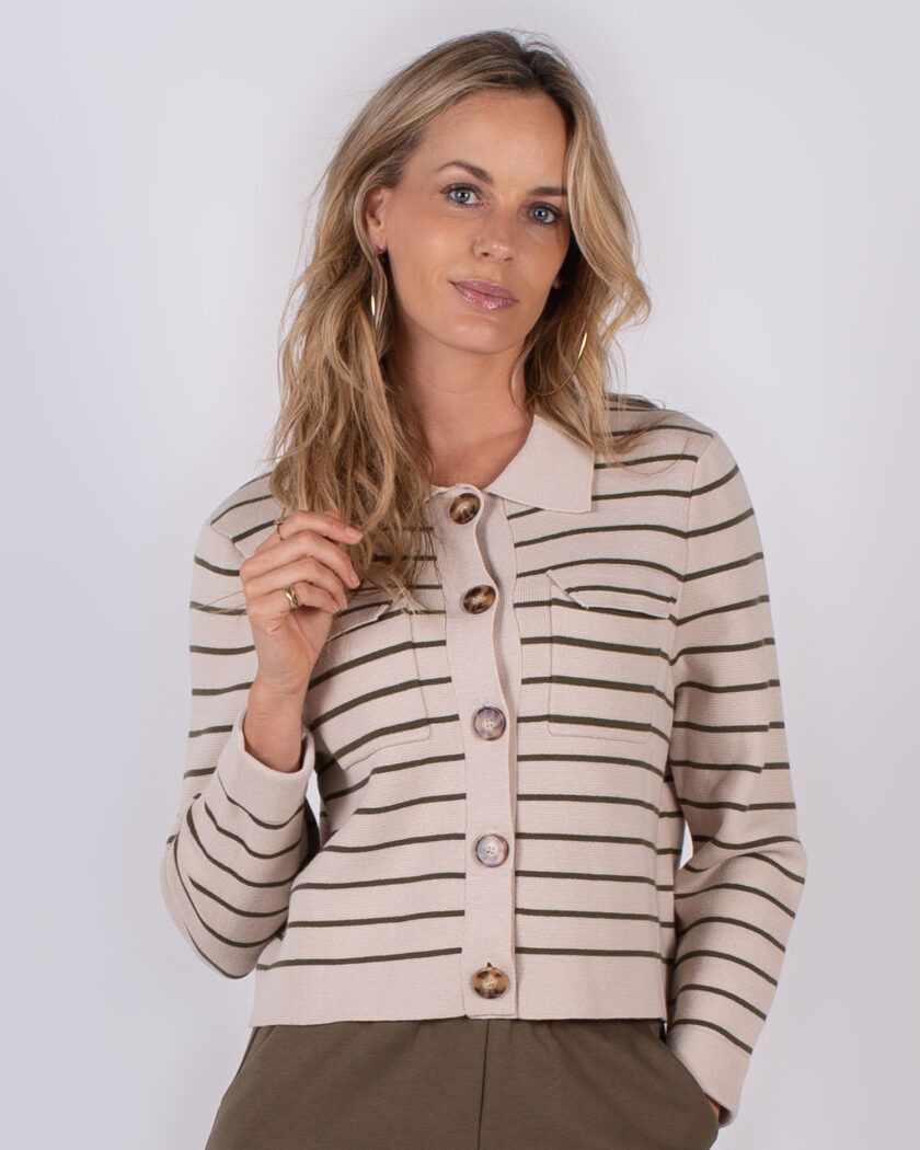 Vrouw draagt een beige vest met donkergroene strepen en grote knopen uit de Studio AW25-26 collectie.