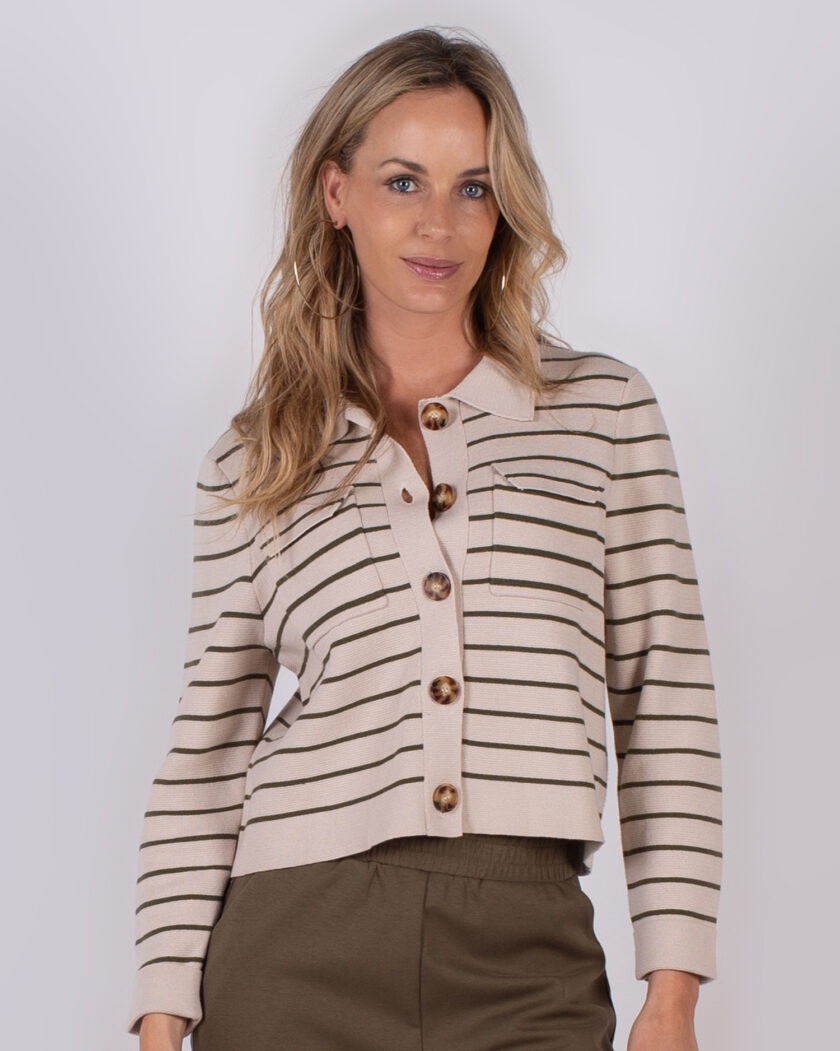 Vrouw draagt een beige vest met horizontale donkergroene strepen en grote knopen uit de Studio AW25-26 collectie.