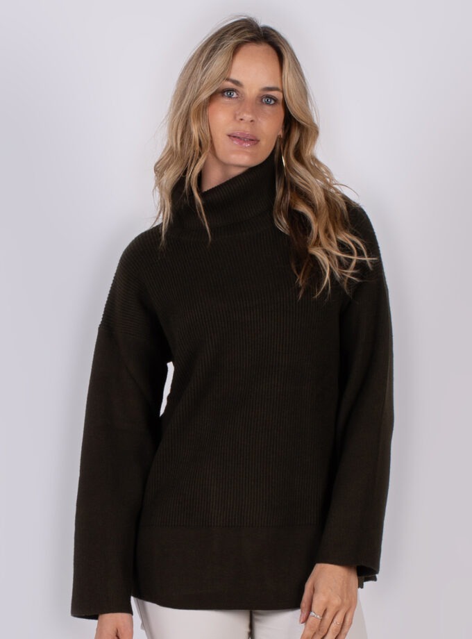 Vrouw draagt een donkerbruine coltrui met ribstructuur uit de Studio AW25-26 collectie.