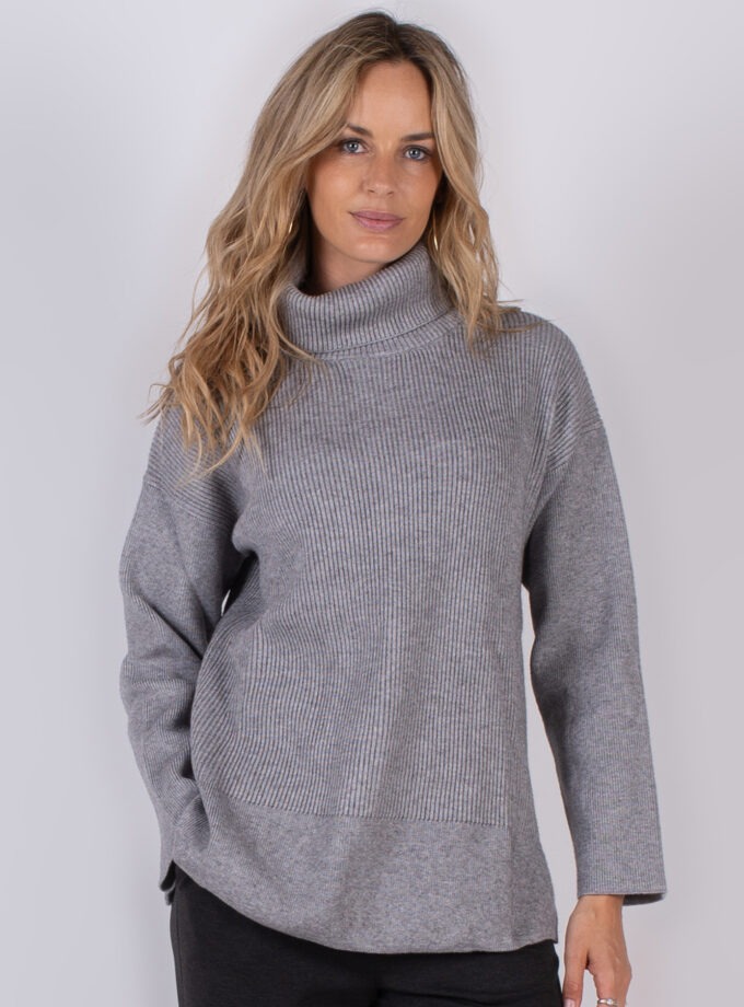 Vrouw draagt een grijze coltrui met ribbelstructuur uit de Studio AW25-26 collectie.