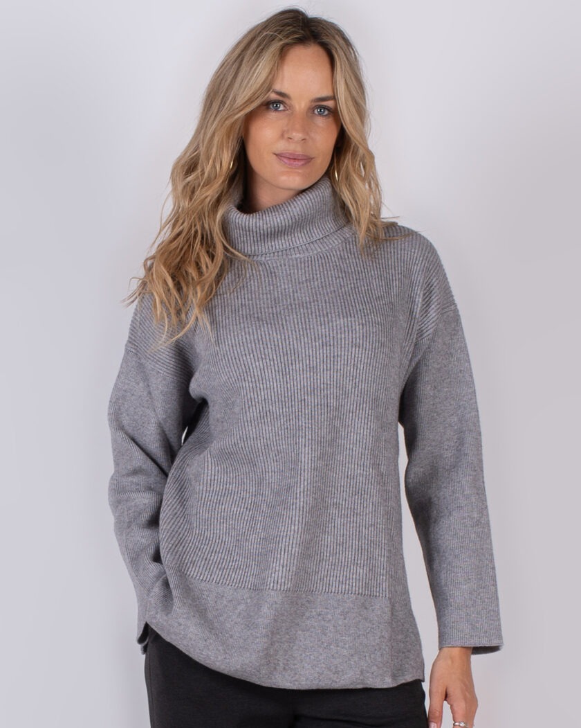 Vrouw draagt een grijze coltrui met ribbelstructuur uit de Studio AW25-26 collectie.