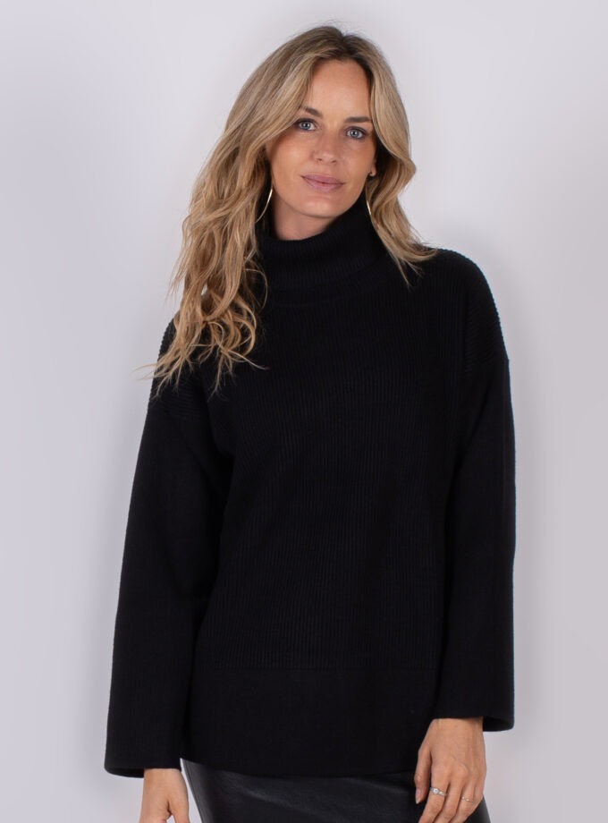 Vrouw draagt een zwarte coltrui met lange mouwen uit de Studio AW25-26 collectie.