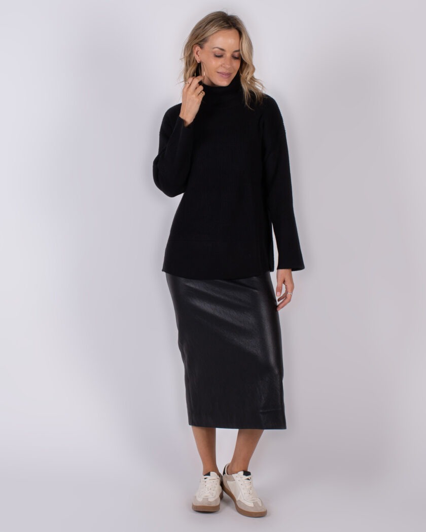 Vrouw draagt een zwarte coltrui en een zwarte midi-rok van leerlook uit de Studio AW25-26 collectie.