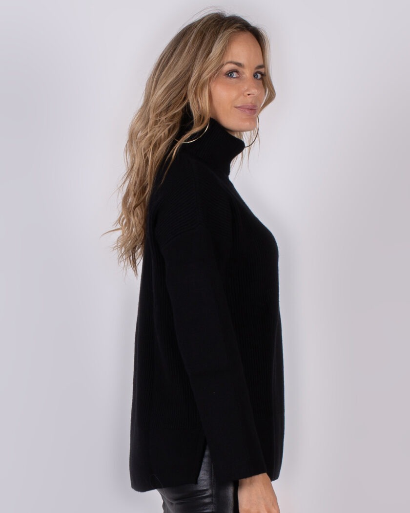 Vrouw in zijaanzicht draagt een zwarte coltrui uit de Studio AW25-26 collectie.