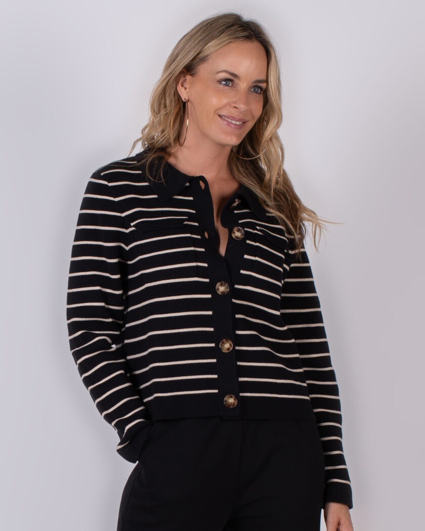 Vrouw met lang blond haar draagt een zwart-wit gestreept vest met grote knopen uit de Studio AW25-26 collectie.