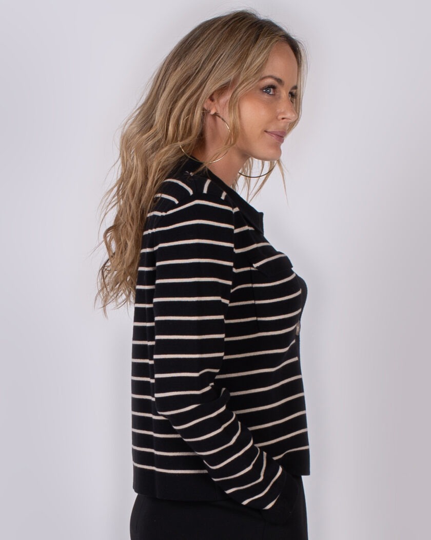 Vrouw in zwarte trui met witte horizontale strepen uit Studio AW25-26 collectie, zijaanzicht.