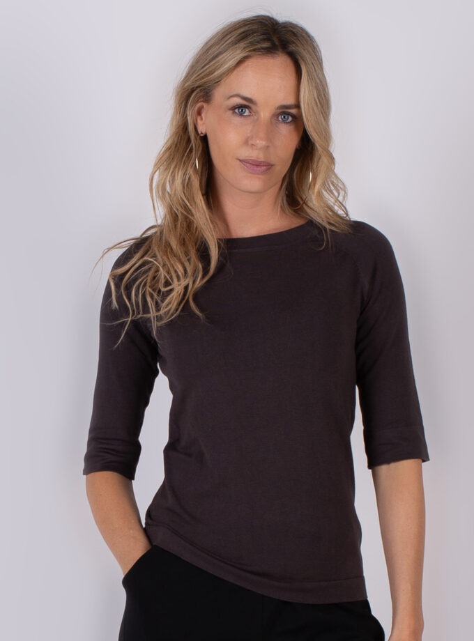 Vrouw draagt een donkerbruin, driekwart mouwshirt uit de Studio AW25-26 collectie.