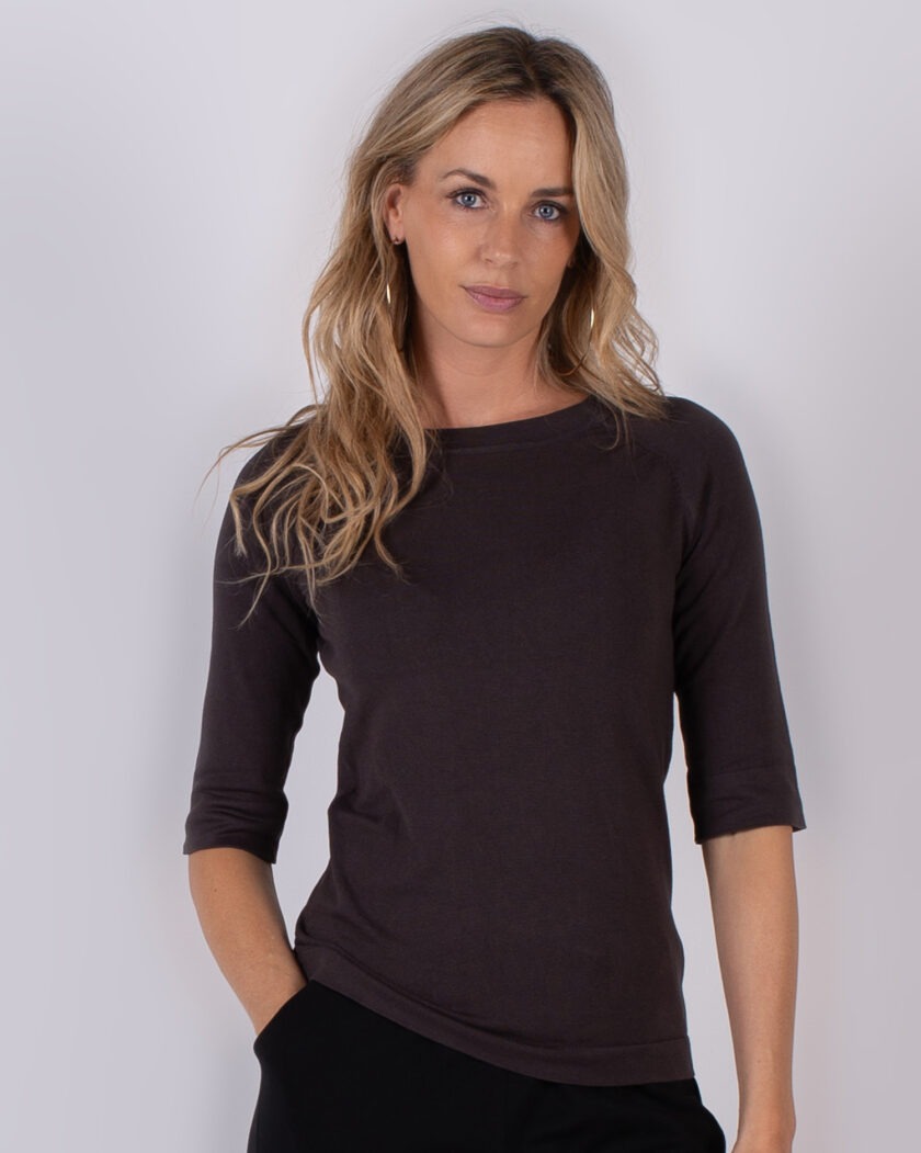 Vrouw draagt een donkerbruin, driekwart mouwshirt uit de Studio AW25-26 collectie.