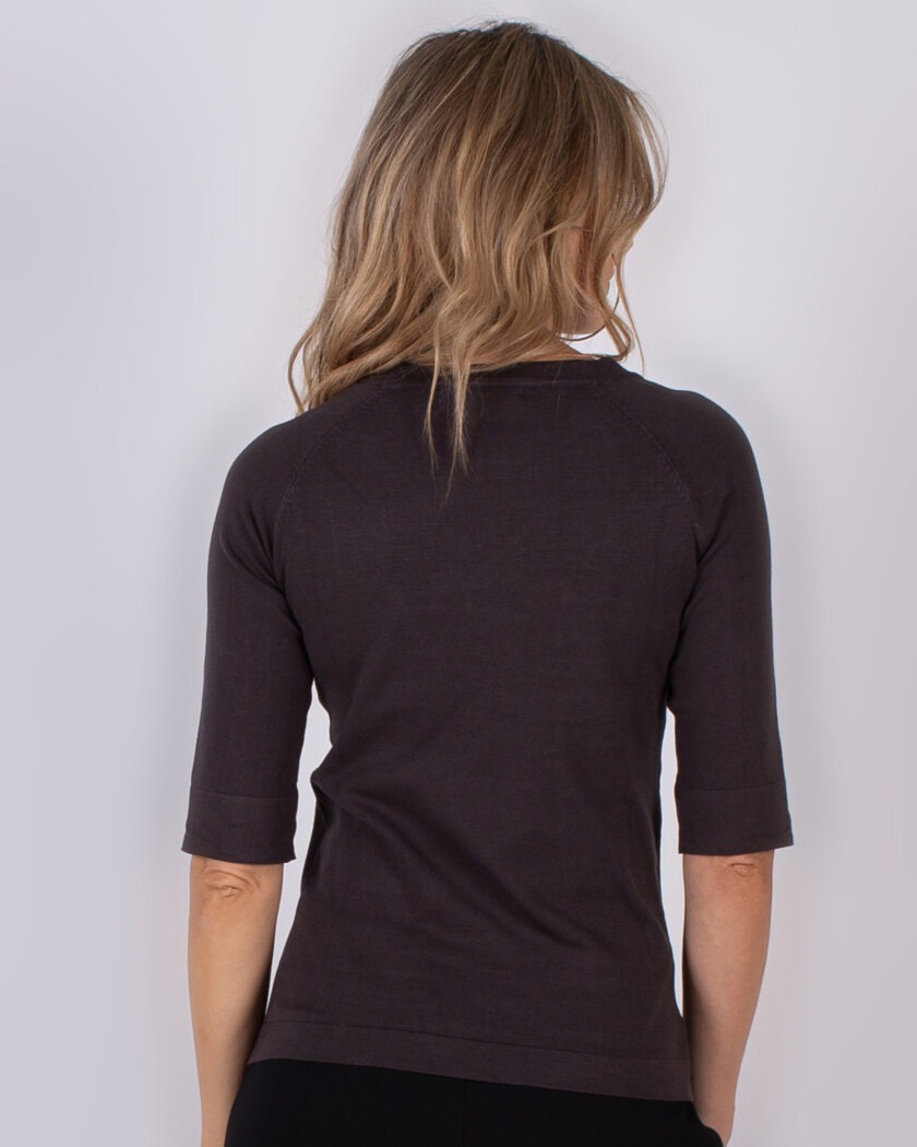 Vrouw met halflang blond haar draagt een donkerbruine top met halflange mouwen, gezien van achteren.