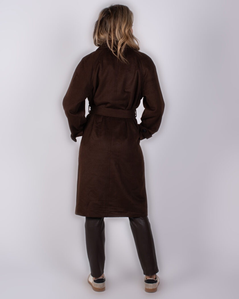 Model van achteren in een donkerbruine jas met ceintuur uit de Studio AW25-26 collectie.