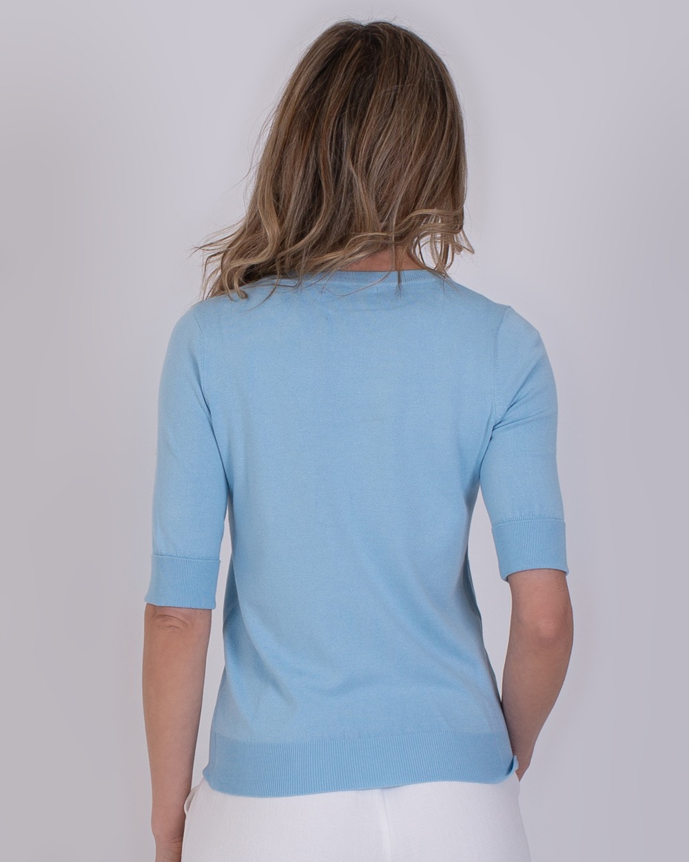 Darwin soft blue 5 Vrouw van achteren gefotografeerd in een lichtblauwe Darwin soft blue trui met halve mouwen.