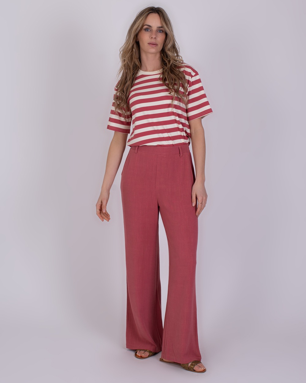 Istanbul raspberry 1 Vrouw draagt een rood-wit gestreept T-shirt en losse frambooskleurige broek uit de Istanbul Raspberry collectie.