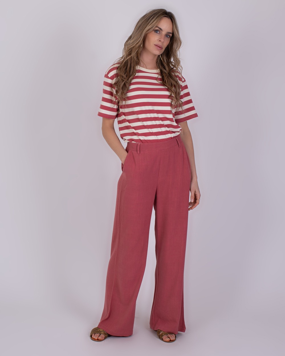 Vrouw draagt een gestreept T-shirt en losse framboosrode broek genaamd 'Istanbul raspberry 2'.