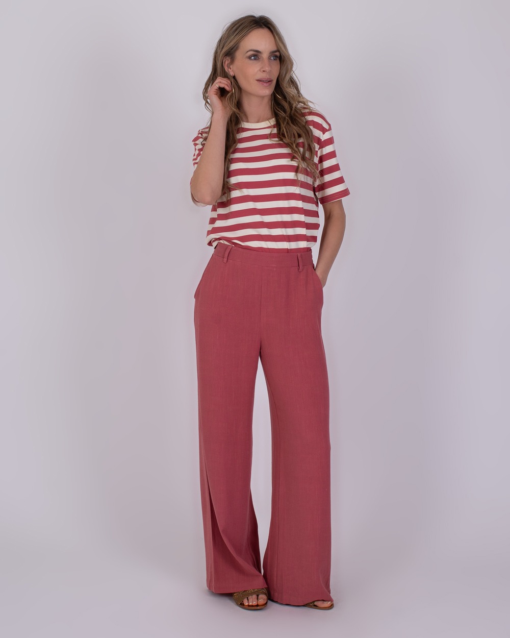 Istanbul raspberry 4 Vrouw draagt een rood-wit gestreept T-shirt en wijde frambooskleurige broek uit de Istanbul raspberry 4 collectie.