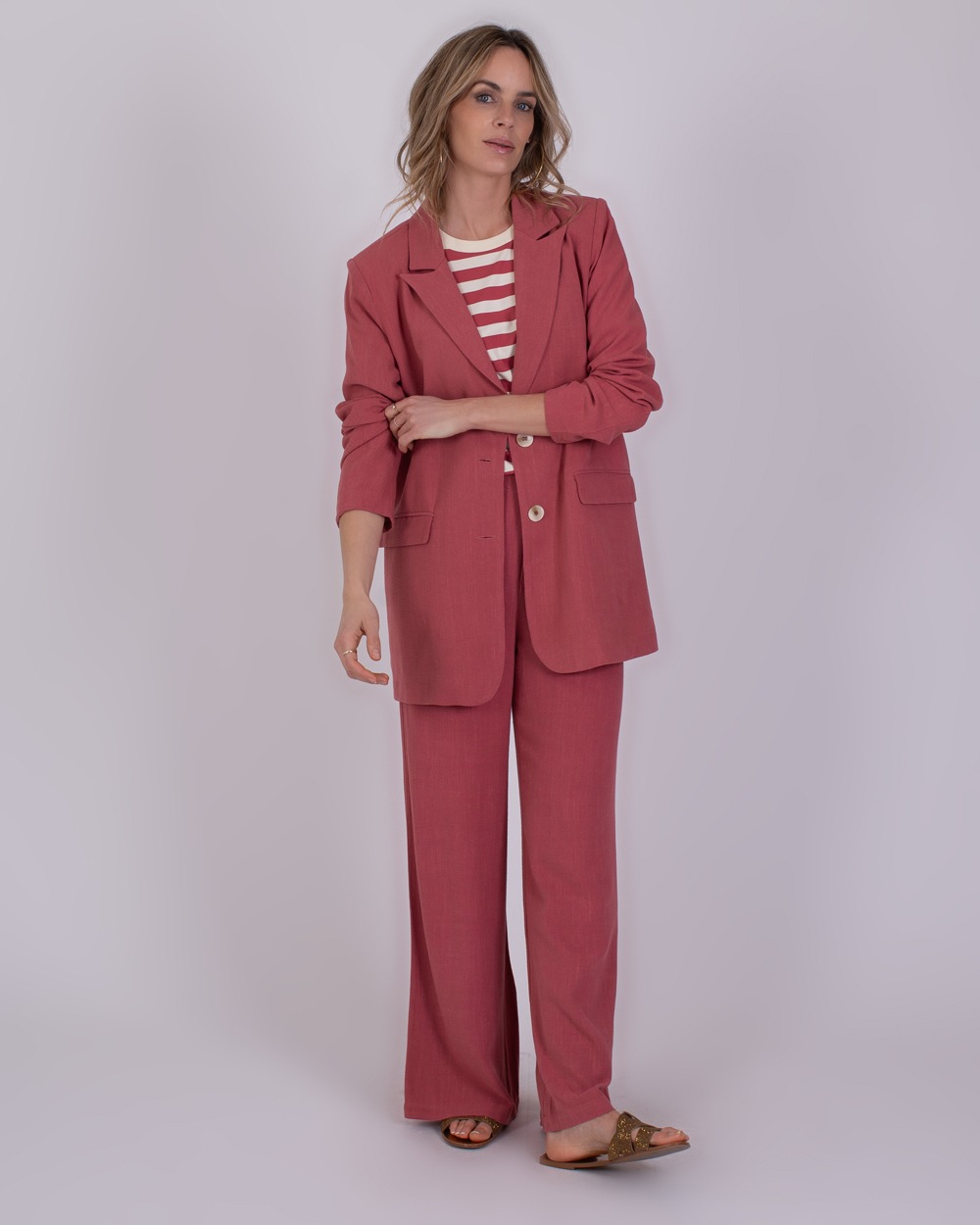 Jodphur raspberry 1 Vrouw draagt een Jodphur raspberrykleurig pak met een rood-wit gestreept shirt en sandalen.