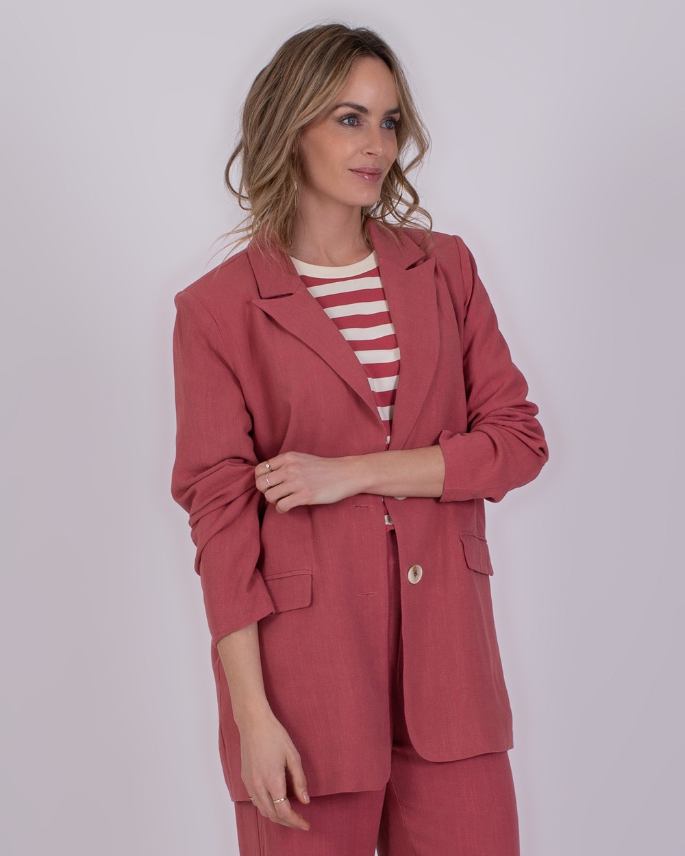 Jodphur raspberry 3 Vrouw in Jodphur raspberrykleurig pak met gestreept shirt poseert tegen een neutrale achtergrond.