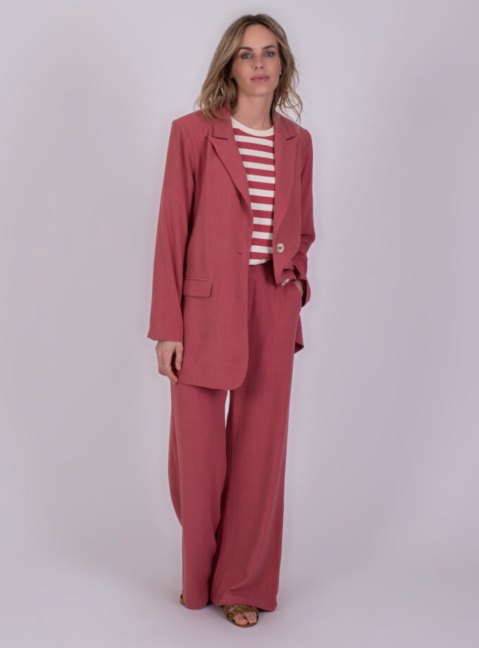 Vrouw draagt een losvallend Jodphur raspberry pak met een rood-wit gestreept shirt.