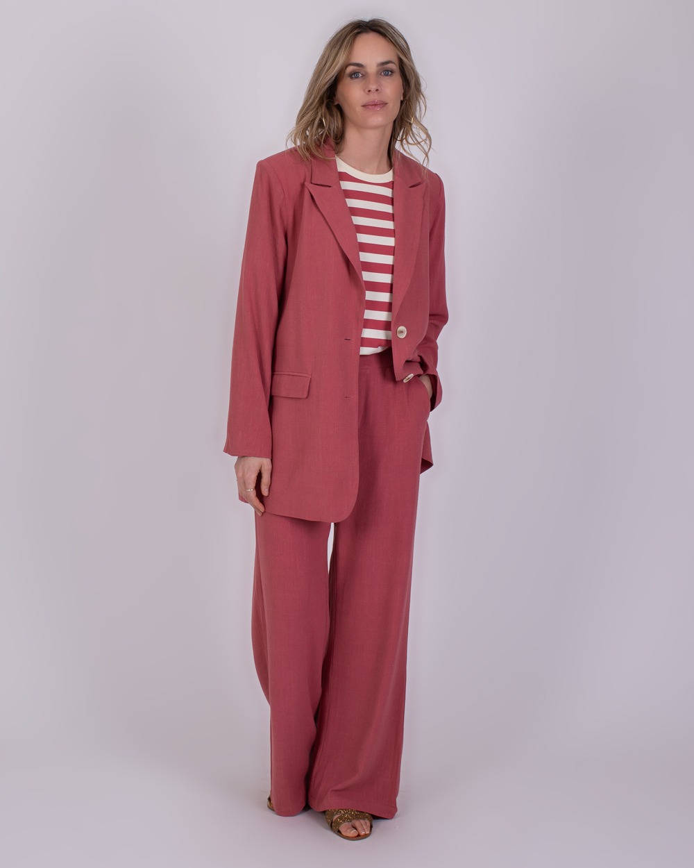 Vrouw draagt een losvallend Jodphur raspberry pak met een rood-wit gestreept shirt.