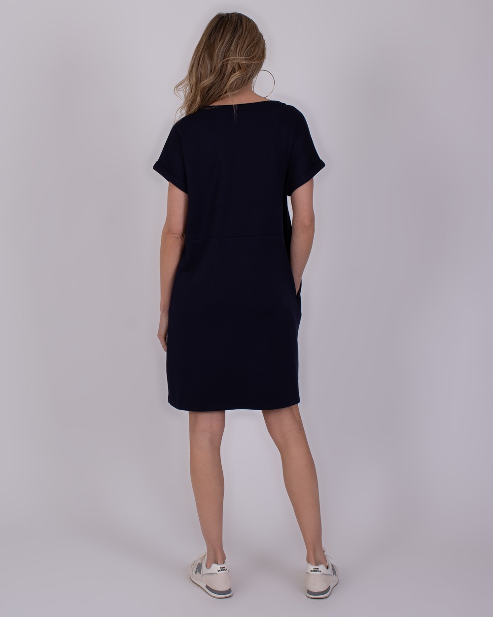 Liverpool navy 3 Vrouw van achteren in een donkerblauwe Liverpool Navy-jurk met korte mouwen en sneakers.