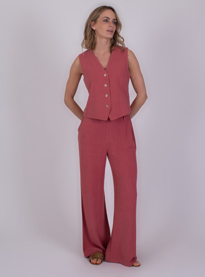 Vrouw draagt een mouwloos roodroze 'Surat Raspberry' gilet met bijpassende wijde broek.